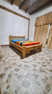 莫姆皮切Casa Gaia: Un Paraiso的一间卧室配有一张带彩色床单的木床