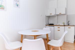索科矿泉村Apartmani Zvirac的一间带桌子和白色椅子的小厨房