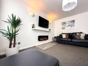 伯明翰Contemporary and Cosy Birmingham Apartment- Free Parking & Wi-FI的客厅配有黑色沙发和植物