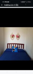 San CarlosSancarlosbeach的卧室配有一张蓝色的床,墙上挂着两朵鲜花