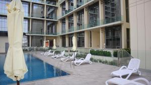 阿布扎比Chalet 2BR Duplex Apartment的一座建筑前的带椅子和游泳池的酒店