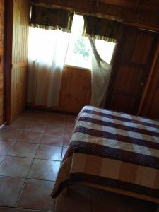 埃博森Raíces del Bolsón的一间卧室配有一张带 ⁇ 子毯子的床