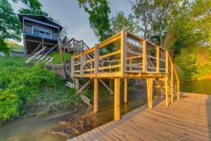 韦科Rustic River Cabin with Dock and Covered Deck!的一座木桥,在河上,有房子