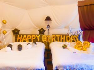 富士河口湖スイートグランピング河口湖的一间卧室设有两张床,带有生日快乐的标志