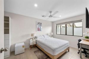 布里斯班Room to rent at the Glasshouse Mountains - Wifi的一间卧室配有一张床、一张书桌和一个窗户。