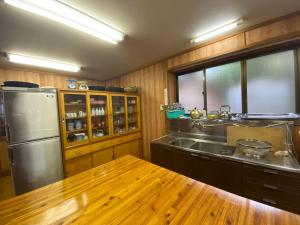 伊那市Irori 新山ふるさと体験館的厨房配有不锈钢冰箱和木桌