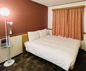 上田市Toyoko Inn Ueda Ekimae的卧室配有白色的床和窗户。