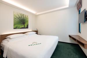 曼谷Maitria Mode Sukhumvit 15 Bangkok - A Chatrium Collection的卧室配有白色的床和绿色地毯。