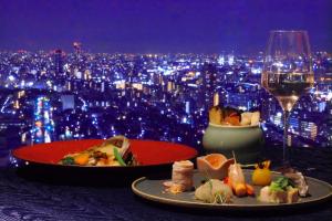 神户神户全日空皇冠广场酒店的一张桌子,上面放着两盘食物和一杯葡萄酒