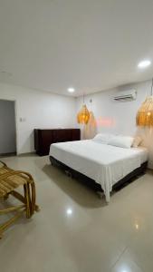 圣玛尔塔Casa campestre con piscina cerca al aeropuerto y la playa的一间卧室配有一张大床和两个吊灯。