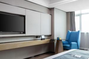 海口宜尚酒店(海口国兴大润发省政府店)的配有电视和蓝椅的酒店客房