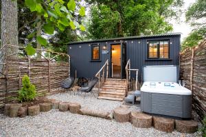 德里门The Mar Huts - The Lomond Hut的一座带热水浴缸的黑色小房子