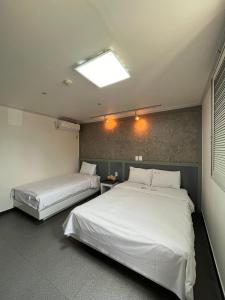 束草市Motel Choo Eok的配有白色床单的客房内的两张床