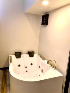 曼谷V20 Boutique Jacuzzi Hotel - SHA Extra Plus的浴室设有白色浴缸,配有金色水龙头