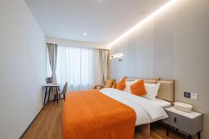 上海客堂涧酒店(上海火车站宝山路地铁站店)的一间卧室配有一张带橙色毯子的大床