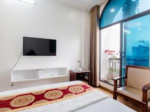 河内Phuong Nam Luxury Hotel Long Bien的一间卧室设有一张床、一台电视和一个窗口。