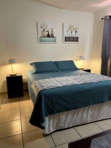 圣萨尔瓦多Casa en Residencial Privado Lomas de San Francisco的一间卧室配有一张带蓝色床单的床和两盏灯。