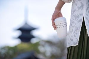 京都OMO3 Kyoto Toji by Hoshino Resorts的手上拿着咖啡的女人