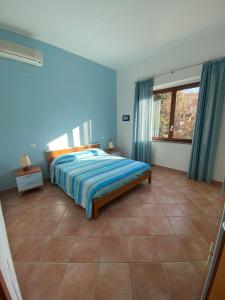 圣温琴佐Villa il Boschetto的一间卧室配有一张蓝色墙壁的床和一扇窗户
