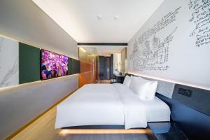 北京北京总部基地CitiGO欢阁酒店的卧室配有白色的床和带绘画的墙壁