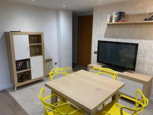 Sant Joan de VilatorradaApartament Sant Jordi的客厅配有桌子、黄色椅子和电视