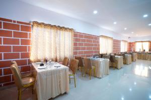 班加罗尔Treebo Trend Galaxy Kings Suites - Hebbal的一间带桌椅的餐厅以及砖墙