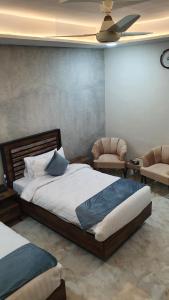 伊斯兰堡Burj Ul Zaki的一间卧室设有一张床铺、两把椅子和天花板