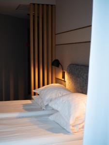 塔林Rija Fonnental Design Hotel Tallinn的一间卧室配有带白色床单和枕头的床。