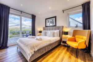 HayfieldNew Build Lodge With Stunning Views of Loch Awe的一间卧室配有一张大床和一张黄色椅子