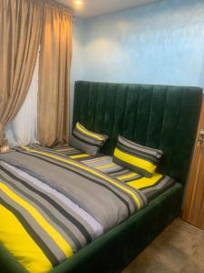 拉各斯BLUE AO HOTEL的一张绿色的床,上面有黄色和黑色的枕头