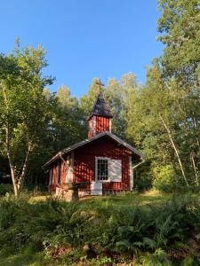 ÅnimskogIngerichte safaritenten aan Zweeds meer op Betteld Sweden的森林中间的红色小屋