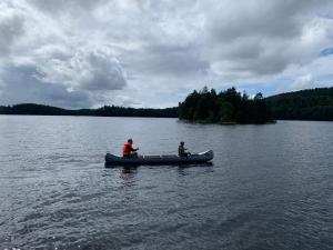 ÅnimskogIngerichte safaritenten aan Zweeds meer op Betteld Sweden的两个人坐在湖上划独木舟