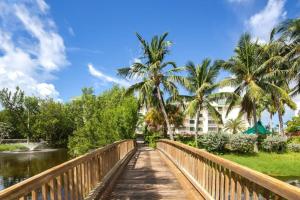 基韦斯特The Barbados by Brightwild-Bright Condo w Pool的一座棕榈树和建筑的河流上的桥梁