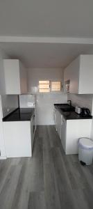 圣埃乌拉利亚Siesta Mar Apartamentos Ibiza的厨房铺有木地板,配有白色橱柜。