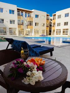 加利布港Port Ghalib Apartments的一张桌子,上面放着一碗水果和鲜花,旁边是游泳池