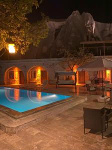 格雷梅Seven Rock Cave Hotel的一座晚上的游泳池,与iguana房子同在