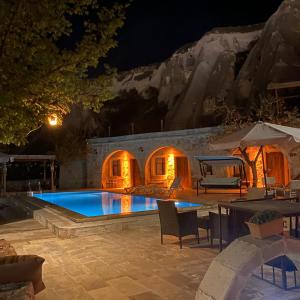 格雷梅Seven Rock Cave Hotel的一个带桌椅的夜间游泳池