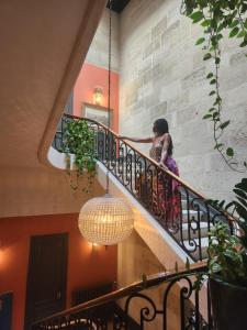 利布尔讷La Maison Mulatô, demeure privée d'hôtes, piscine & spa Libourne, Saint-Emilion的一位女士在楼梯上用吊灯行走