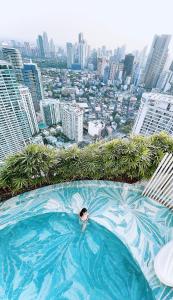 马尼拉The Serene Escape Rockwell Makati City View 1BR的城市顶端游泳池游泳的人