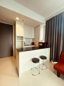 巴淡岛中心Vanilla One Residence Apartment Batam的一间厨房,里面设有两张凳子和一个柜台