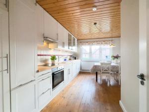 瓦尔斯罗德Backhus Nordkampen的厨房配有白色橱柜和木制天花板