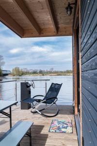 汉堡Luxus-Hausboot DIVA mit Kamin的坐在水边的码头上的椅子