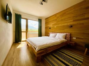 SohodolCasa Aluna Duo的一间卧室配有一张带木墙和窗户的床。
