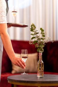 Langenegg科龙兰格尼格酒店的坐在桌子上拿着一杯葡萄酒的女人
