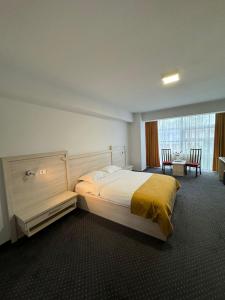 皮特什蒂Hotel Yaky Center的一间卧室配有一张大床和一张桌椅