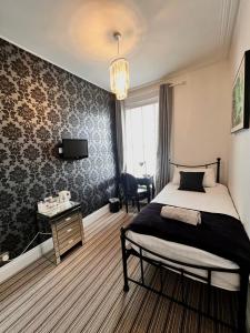 伯恩茅斯竹酒店的一间卧室配有一张床、一张书桌和一台电视。