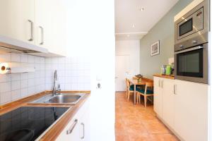 瓦尔内明德斯特兰德纳公寓的厨房配有白色橱柜、水槽和桌子