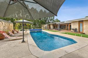 托基Swim spa and play tennis at Relaxing family retreat的一个带遮阳伞和椅子的游泳池