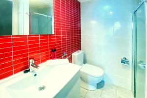BeniarbeigVilla Pomera Dos by Villa Plus的浴室设有水槽、卫生间和红色瓷砖。