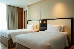 浦那DoubleTree by Hilton-Pune Chinchwad的配有白色床单的酒店客房内的两张床